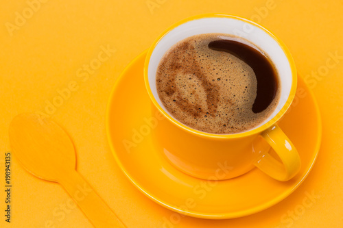 yellow cup with a drink of coffee with foam on a yellow background