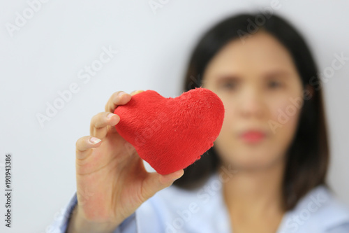 Woman in blue dress hold a red heart in hand.