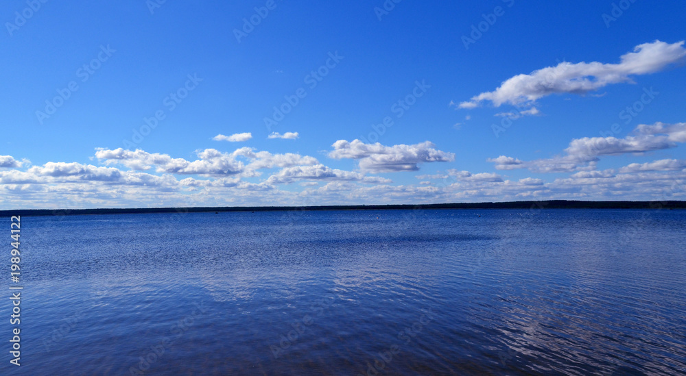 Summer landscape. Bright blue background with clouds and blue lake. 
