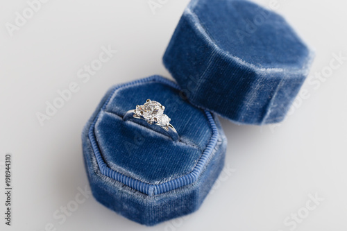 White golden wedding ring with diamonds in blue vintage velvet ring box on white background