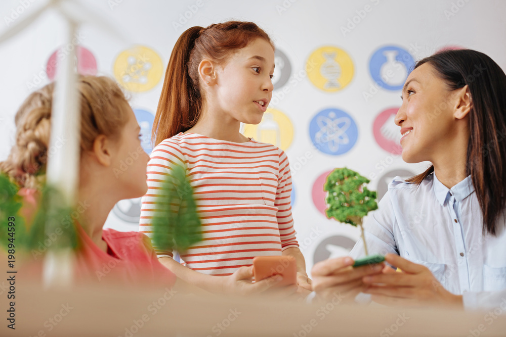 Informative chat. Adorable teenage girl chatting with her teacher and classmate about ecology and deforestation after the class while expressing her own opinion Informative chat. Adorable teenage girl chatting with her teacher and classmate about ecology and deforestation after the class while expressing her own opinion