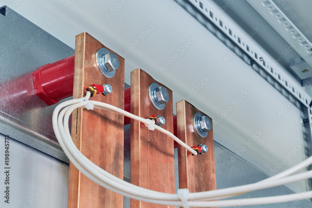 Electrical wires are connected to copper busbars. Busbars are fixed to
