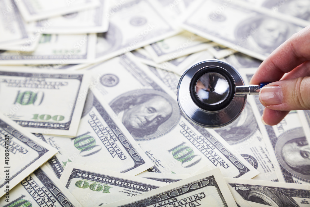 Female hand with a stethoscope on dollars Female hand with a stethoscope on dollars