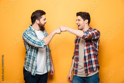 Portrait of a two happy young men giving fist bump