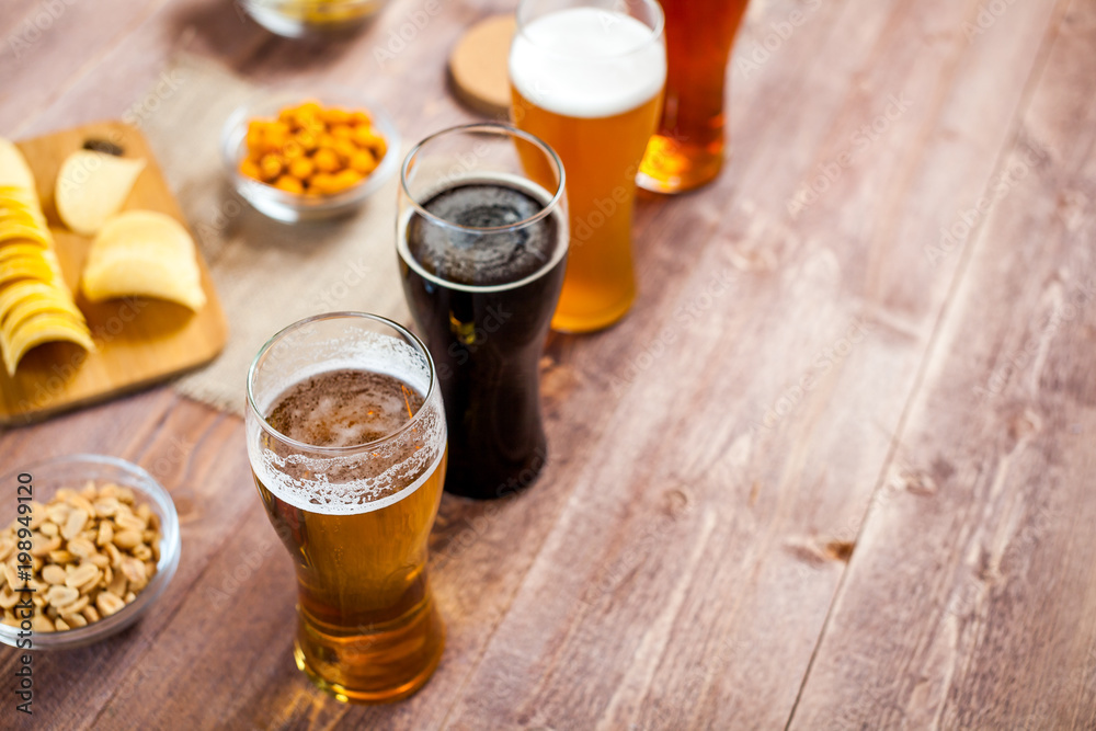 glasses of light and dark beer with assorted snacks on a wooden table background with copy space for text. bachelor party, pub, bar or degustation concept glasses of light and dark beer with assorted snacks on a wooden table background with copy space for text. bachelor party, pub, bar or degustation concept