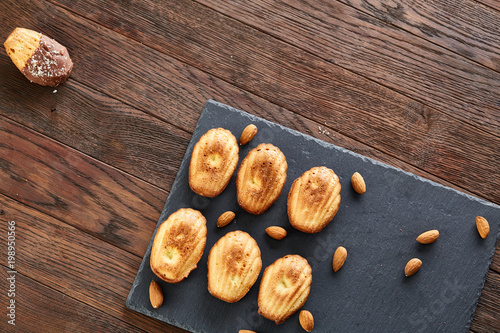 Freshly baked almond cookies with almond on stone board over wooden background, top view, selective focus.
