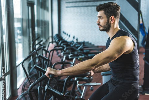 Side view of young sportsman doing workout on exercise bike in sports center © LIGHTFIELD STUDIOS