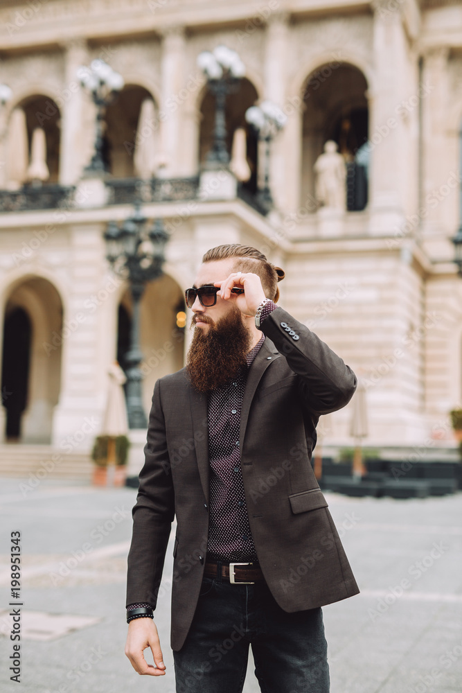 Young man with beard in classical yacht dressed stylish in the center.peyes has sunglasses