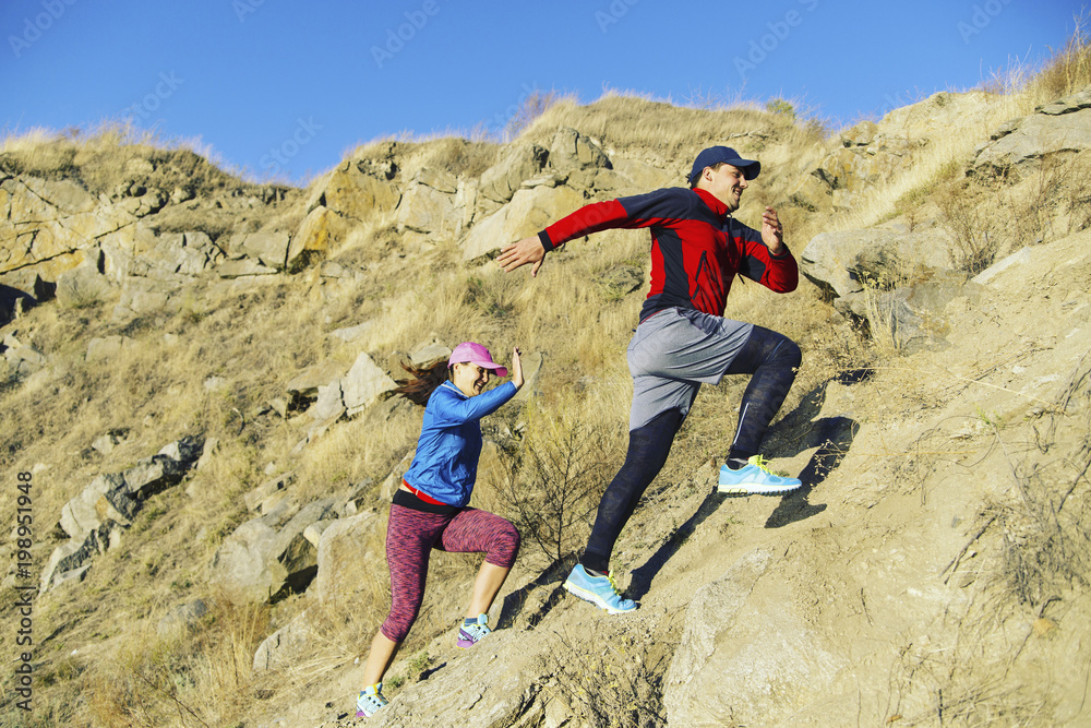 Trail running couple runners racing on mountain path in volcanic rocks nature landscape in summer outdoor. Ultra running race run.