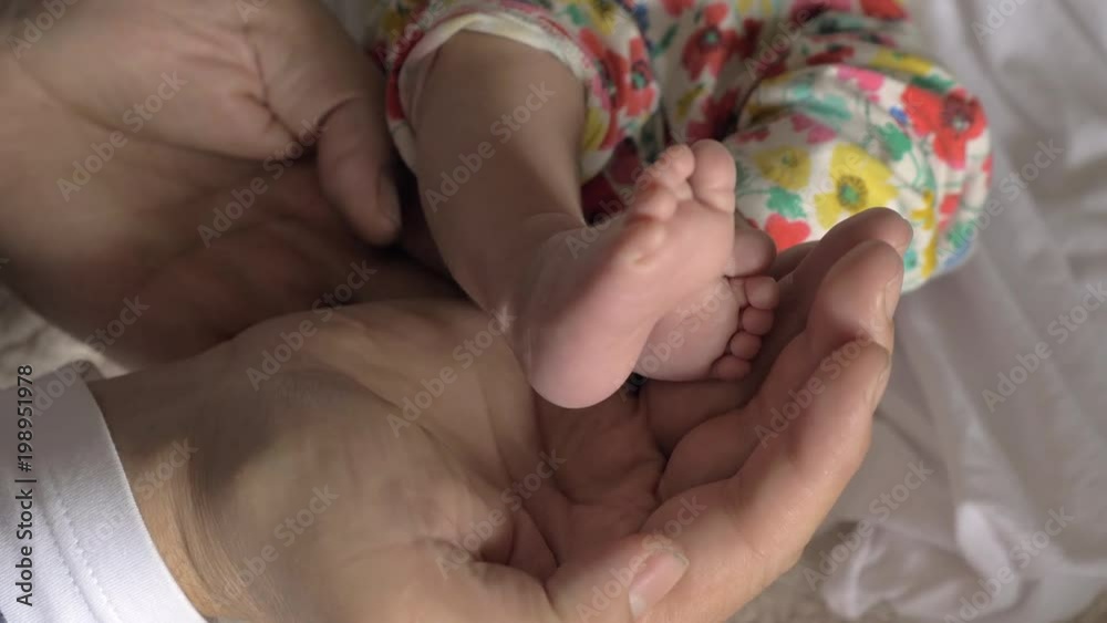 Close-up shot of fathers hands holding little feet of newborn baby. Family love and care. Happy parenthood Close-up shot of fathers hands holding little feet of newborn baby. Family love and care. Happy parenthood