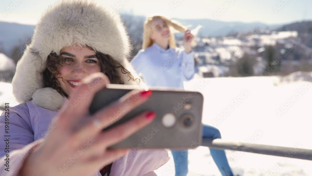 Girls friends making mobile photo at snowy mountain landscape Girls friends making mobile photo at snowy mountain landscape