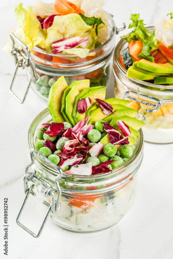 Fresh salads in jar with fresh vegetables and healthy dressings, on white marble table, copy space Fresh salads in jar with fresh vegetables and healthy dressings, on white marble table, copy space