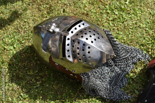 Medieval knight's helmet (bascinet) with face guard visor (klappvisor) and chainmail protection (aventail, camail) on a green grass. photo