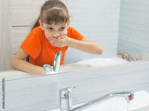 The girl rinses her mouth after brushing her teeth