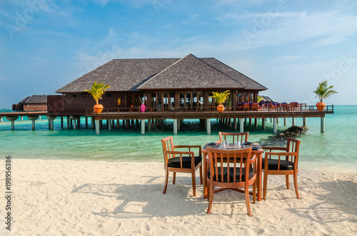 Table and chairs at restaurant at the background of water bungalows  Maldives island