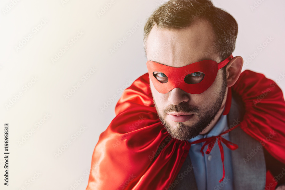serious super businessman in mask and cape looking at camera isolated on white serious super businessman in mask and cape looking at camera isolated on white