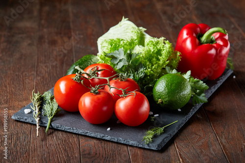 Artistic still life of assorted fresh vegetables and herbs on rustic wooden background, top view, selective focus.