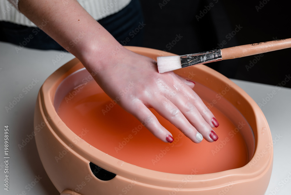Photo Female hands in a paraffin wax bowl
