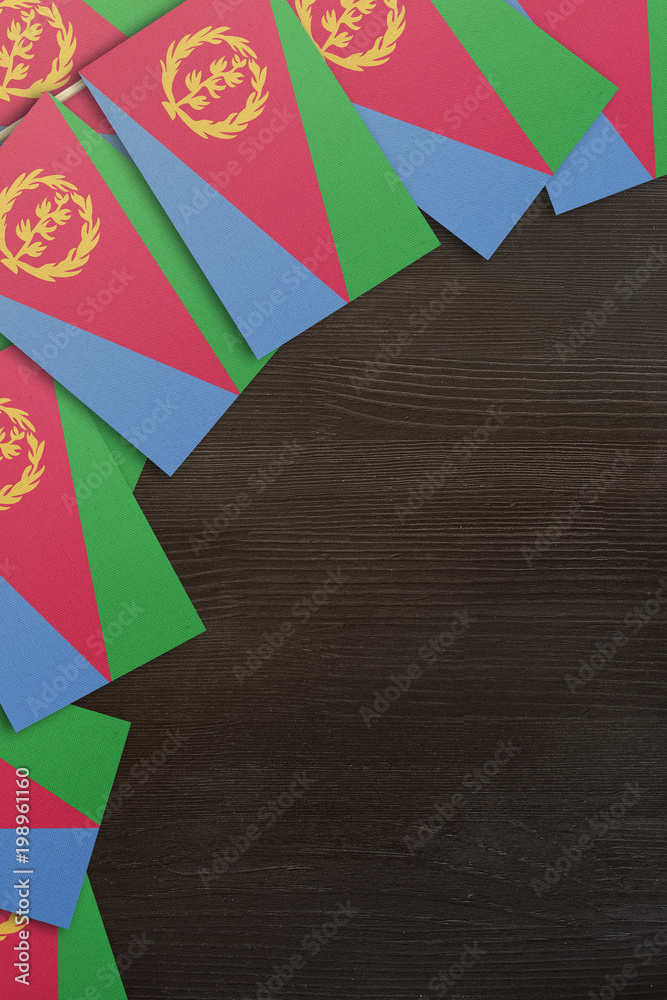 Naklejka premium Eritrea small flags framing a wood texture background with copy space