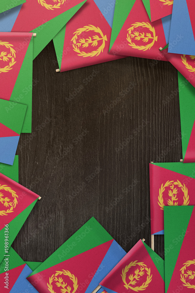 Eritrea small flags framing a wood texture background with copy space Eritrea small flags framing a wood texture background with copy space