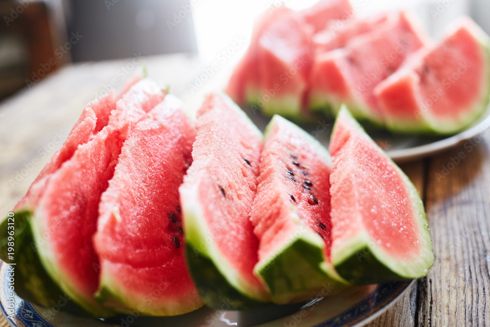 sliced slices of ripe juicy watermelon lie on a plate on a wooden table. small depth of field. sliced slices of ripe juicy watermelon lie on a plate on a wooden table. small depth of field.