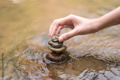 Canvas Print Close up hand to doing Stone stacked in water river