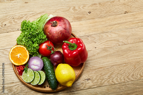 Still life of fresh organic vegetables on wooden plate over wooden background, selective focus, close-up