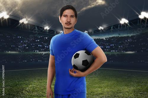 Handsome asian football player with soccer ball