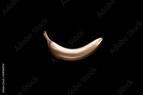 Fototapeta Złoty banan na czarnym tle. Koncepcja kreatywnych z owocami.