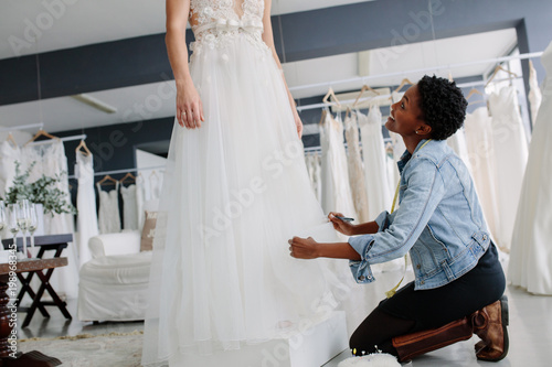 Smiling woman making adjustment to bridal gown photo