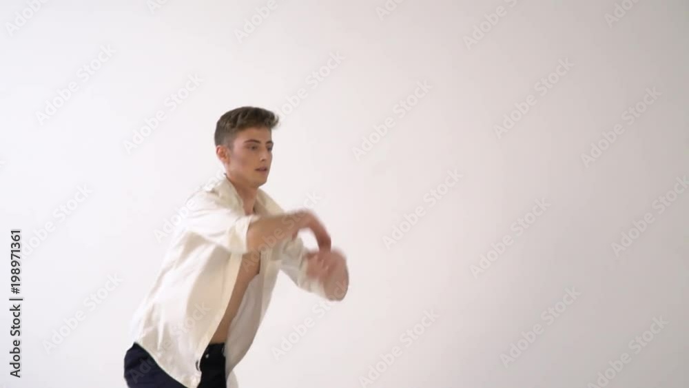 Handsome man in white shirt dancing against white background, slow motion Handsome man in white shirt dancing against white background, slow motion