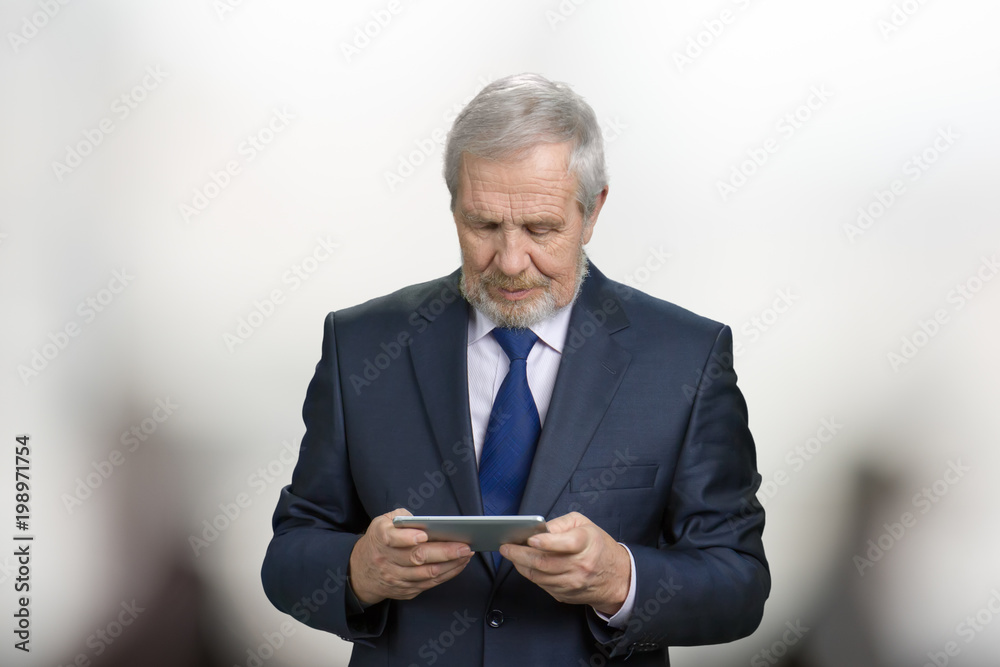 Old polititian is holding smartphone with both hands. Bright blurred background. Old polititian is holding smartphone with both hands. Bright blurred background.
