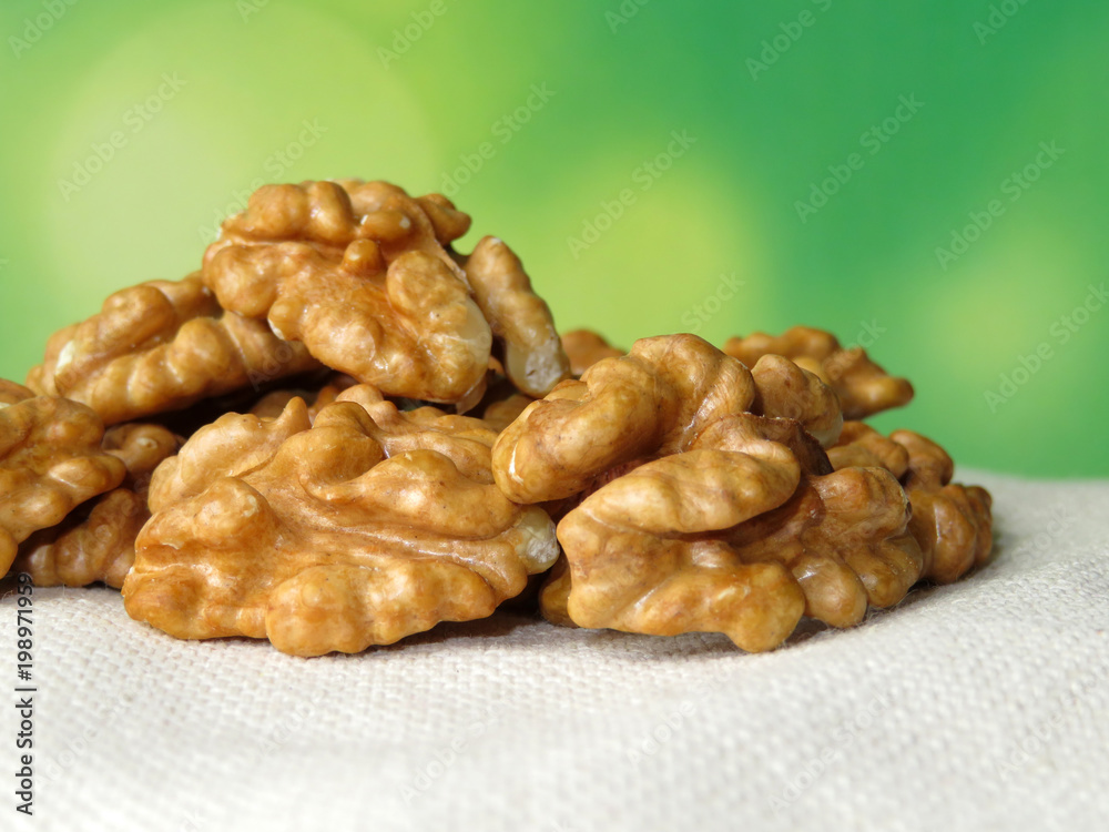 Walnuts on white burlap on green natural background. Beautiful walnut kernels with free copy space. Healthy diet Walnuts on white burlap on green natural background. Beautiful walnut kernels with free copy space. Healthy diet