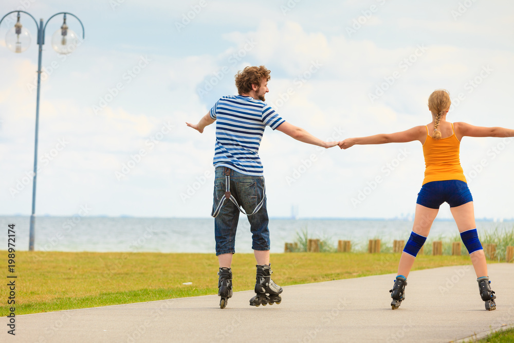 Young couple on roller skates riding outdoors