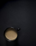 on a black dark background cup of black with coffee and milk vignetting vertical