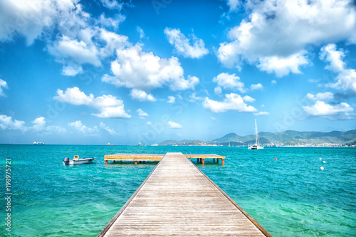 Pier in turquoise sea and blue sky with white clouds in philipsburg, sint maarten. Freedom, perspective and future. Beach vacation at Caribbean, wanderlust