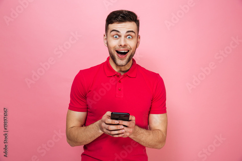 Portrait of an excited young man holding mobile phone © Drobot Dean