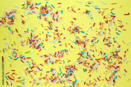 Multicolored confetti on a yellow background top view