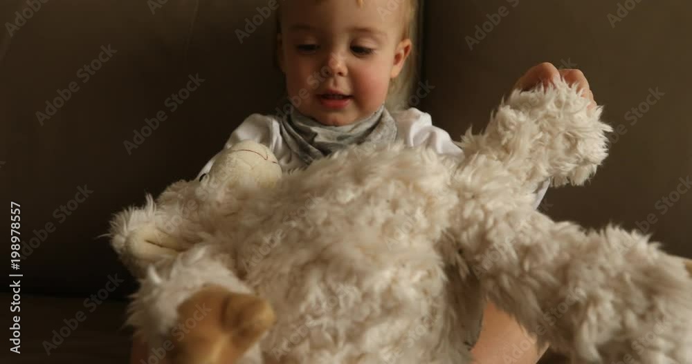 Portrait of lovely laughing baby boy sitting on couch and playing soft toy Portrait of lovely laughing baby boy sitting on couch and playing soft toy
