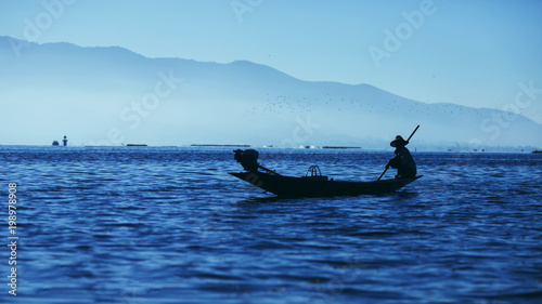Silhouette of a fisherman on Inle Lake, Burma. Background cascade of mountains and red dawn. © Maksim Chekmarev