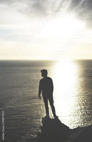 man observes the sea at sunset from high place