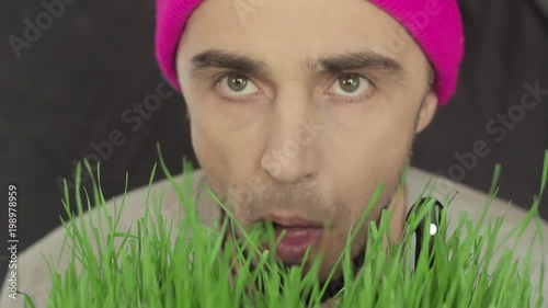 the vegan guy in a bright hat eats green grass photo