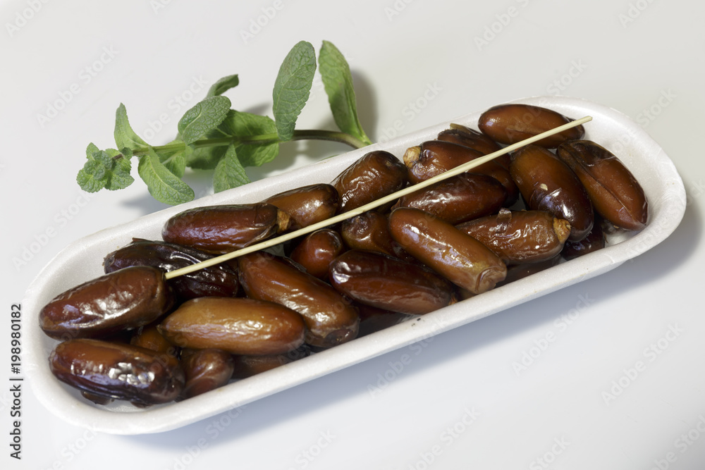 Dates, packed in plastic container, ready for sale, white background. Business concept. Close-up. Dates, packed in plastic container, ready for sale, white background. Business concept. Close-up.