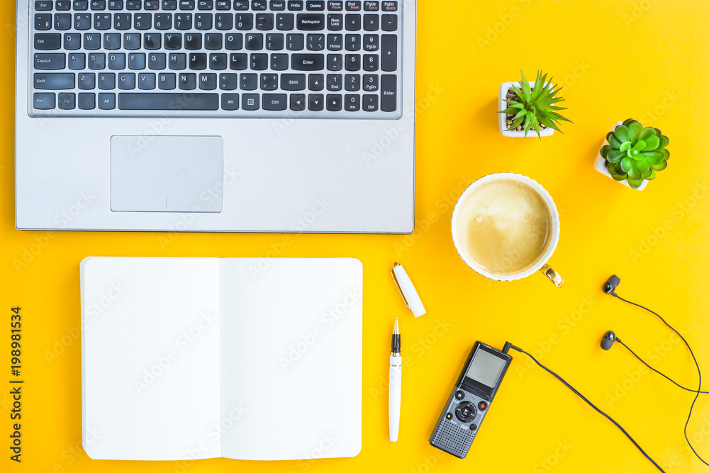 Φωτογραφία The workplace of the journalist is a laptop, a dictaphone, headphones, a notebook, a pen and green plants on a yellow background