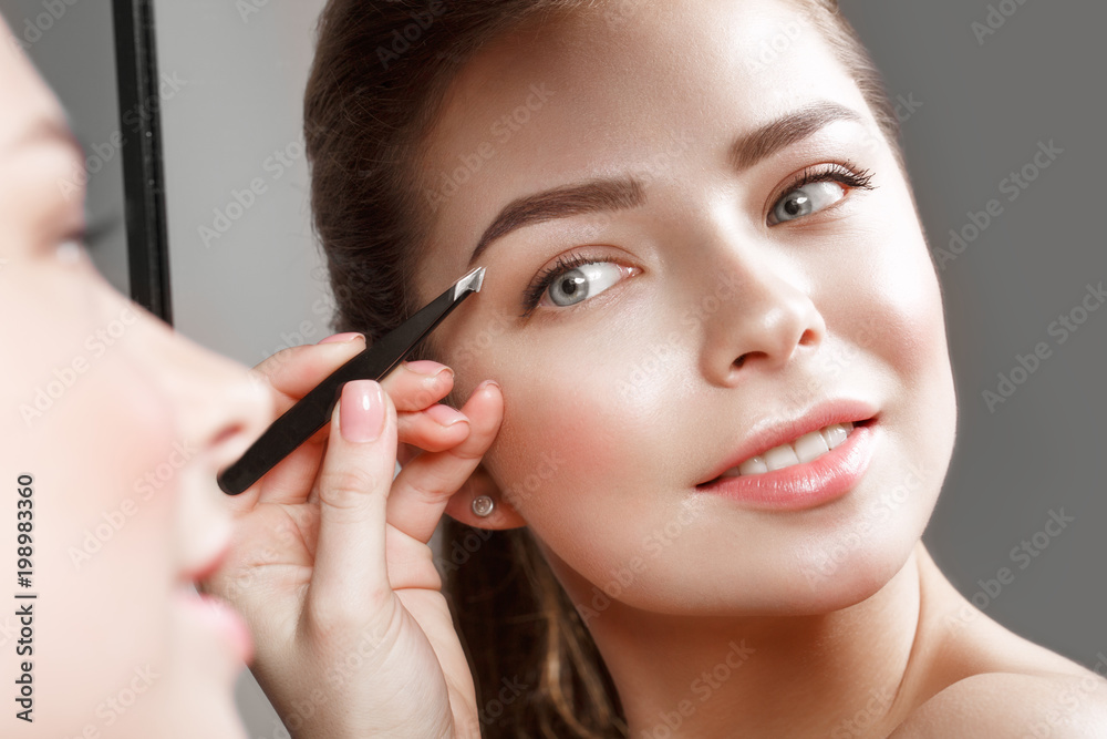 Beautiful girl makes herself a make-up in the mirror. Beauty face. Photo taken in studio Beautiful girl makes herself a make-up in the mirror. Beauty face. Photo taken in studio