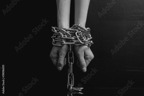 Black and white minimalistic image. women's hands chained close-up on a black background, toned to a retro film
