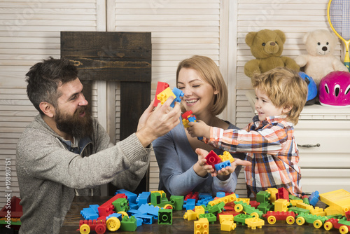 Young family play game with construction blocks.