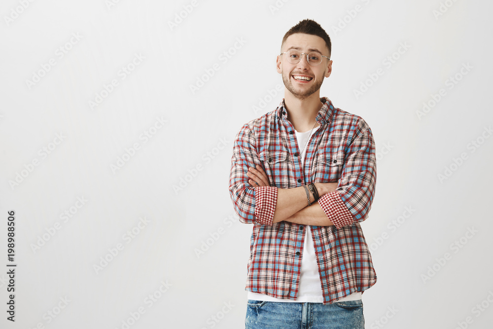Caucasian macho man standing with crossed hands and smiling with lifted eyebrows, listening to someone but doubting words, standing over gray background. Teacher do not believe in student excuse