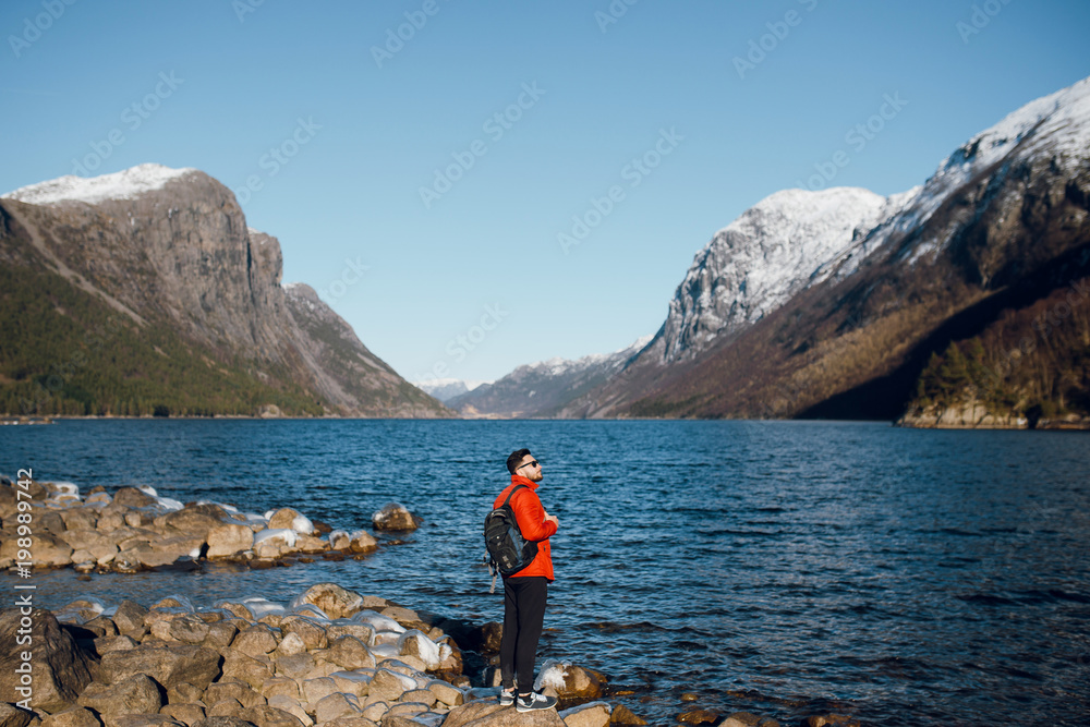 Man standing on the stones alone at fjord in Norway, Travel lifestyle emotions vacations outdoor, scandinavian nature