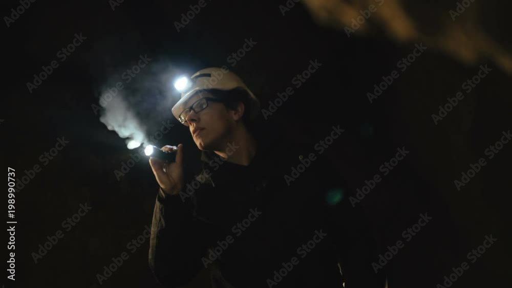 The speleologists with flashlight exploring the cave with fear